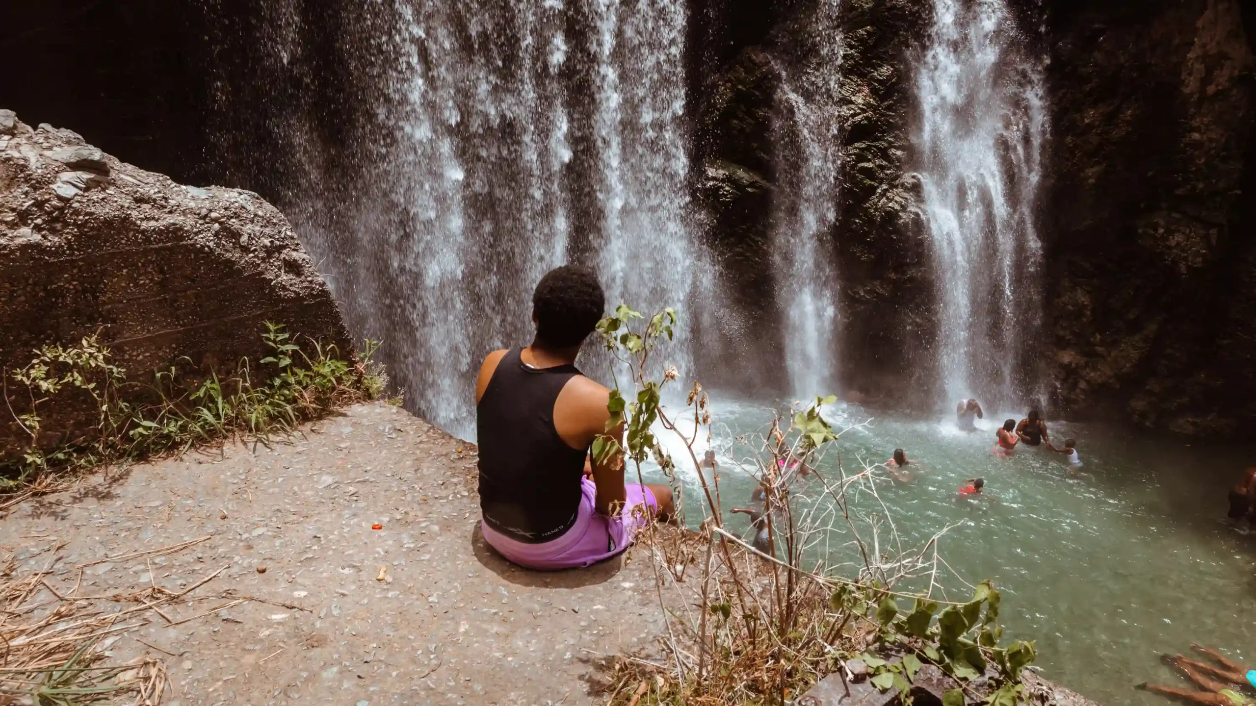 A woman sitting on the edge of a waterfall, enjoying the serene view.